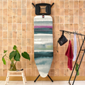 Decorative ironing board with abstract design against a wooden wall.